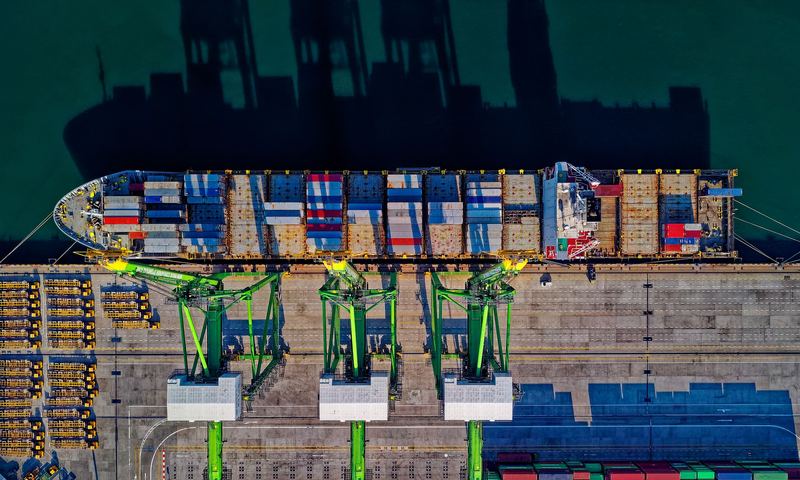 Aerial view of a container ship at a port with cranes